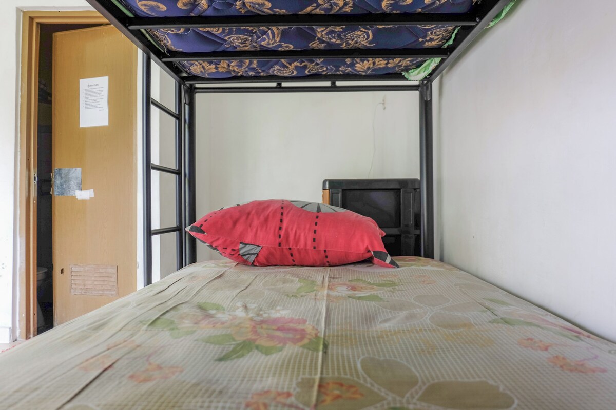 A small room with a bed, a television, and a door.