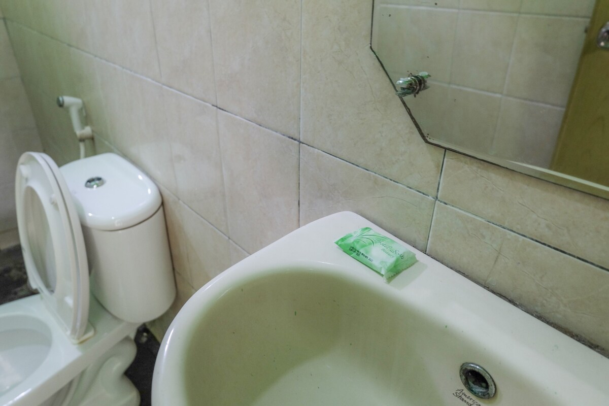 A bathroom with a toilet, a sink, and a mirror.