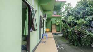 A narrow corridor with a blue bench, green walls, and a small table. - Umah Hijau Tabanan (Tabanan)