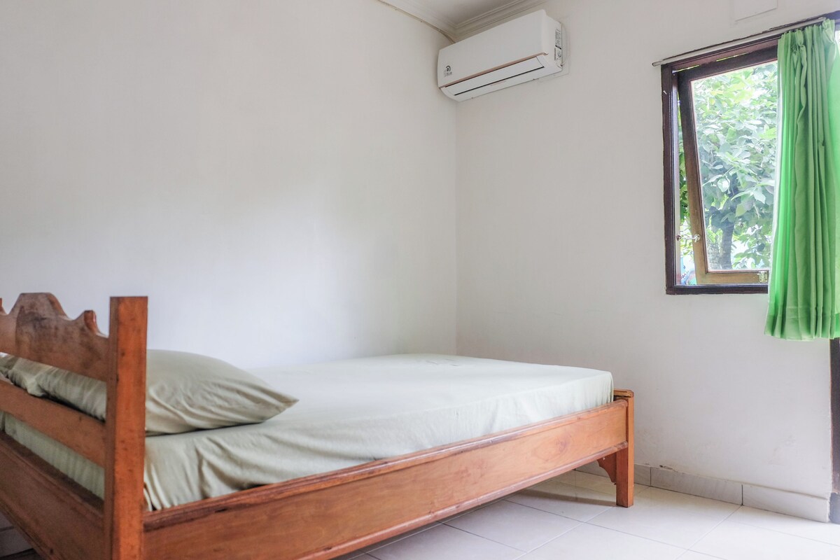 A single bed with a wooden frame and a green curtain.
