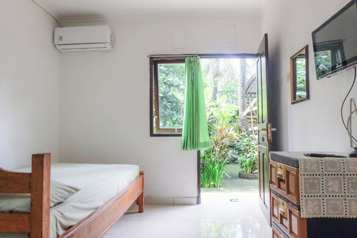 A room with a bed, a TV, and a window with a curtain.