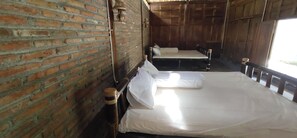 A room with two beds, a brick wall, and wooden paneling. - Omah Regeng (Sumbermulyo)