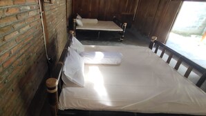 A room with a brick wall, a wooden bed with white bedding, and a window with a view. - Omah Regeng (Sumbermulyo)