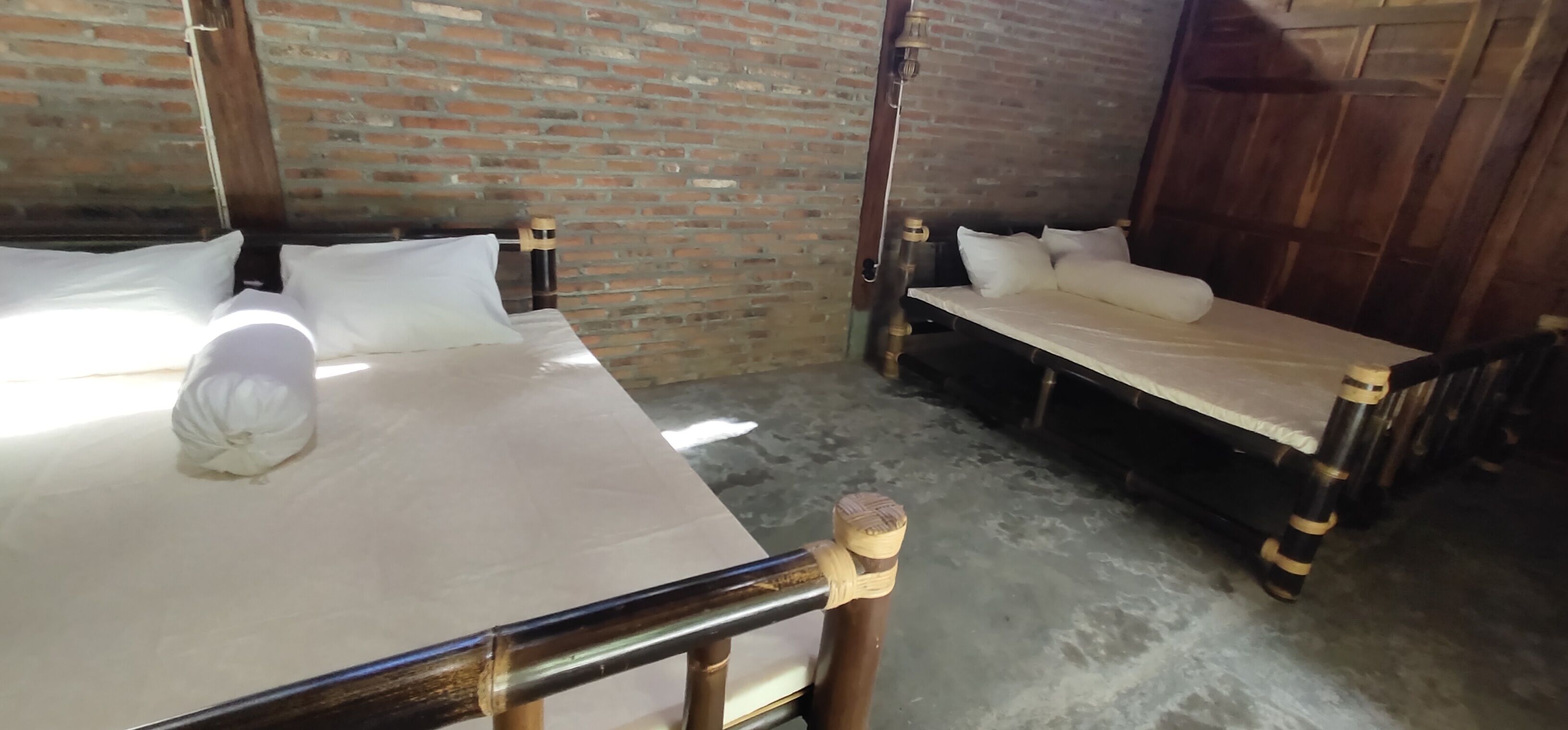 A room with two beds, a brick wall, and a wooden door.