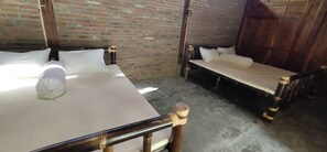 A room with two beds, a brick wall, and a wooden door. - Omah Regeng (Sumbermulyo)