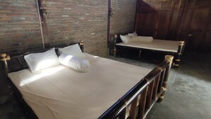 A room with two wooden beds against brick walls, each with a wooden headboard and white bedding. - Omah Regeng (Sumbermulyo)