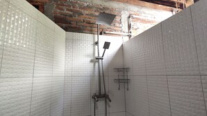 A bathroom with white tiled walls, a shower area, and a visible brick ceiling. - Omah Regeng (Sumbermulyo)