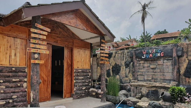 Un edificio de madera rústica con un letrero que dice 'WILUJENG SUMPING'.