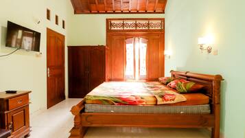A bedroom with a wooden bed, a television on the wall, and a wardrobe.
