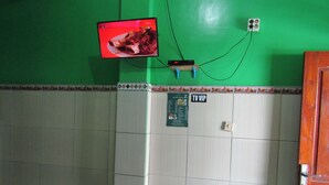 A room with a green wall, a mounted television displaying a meal, a TV VIP sign, and a menu board. - Losmen Kinasih Puncak & Gazebo Pandang by Zuzu (Parangtritis)