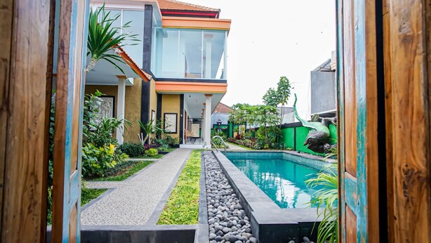 A modern house with a swimming pool, surrounded by greenery and a pathway leading to the entrance. - Bagus Kadek Guesthouse (Jimbaran)