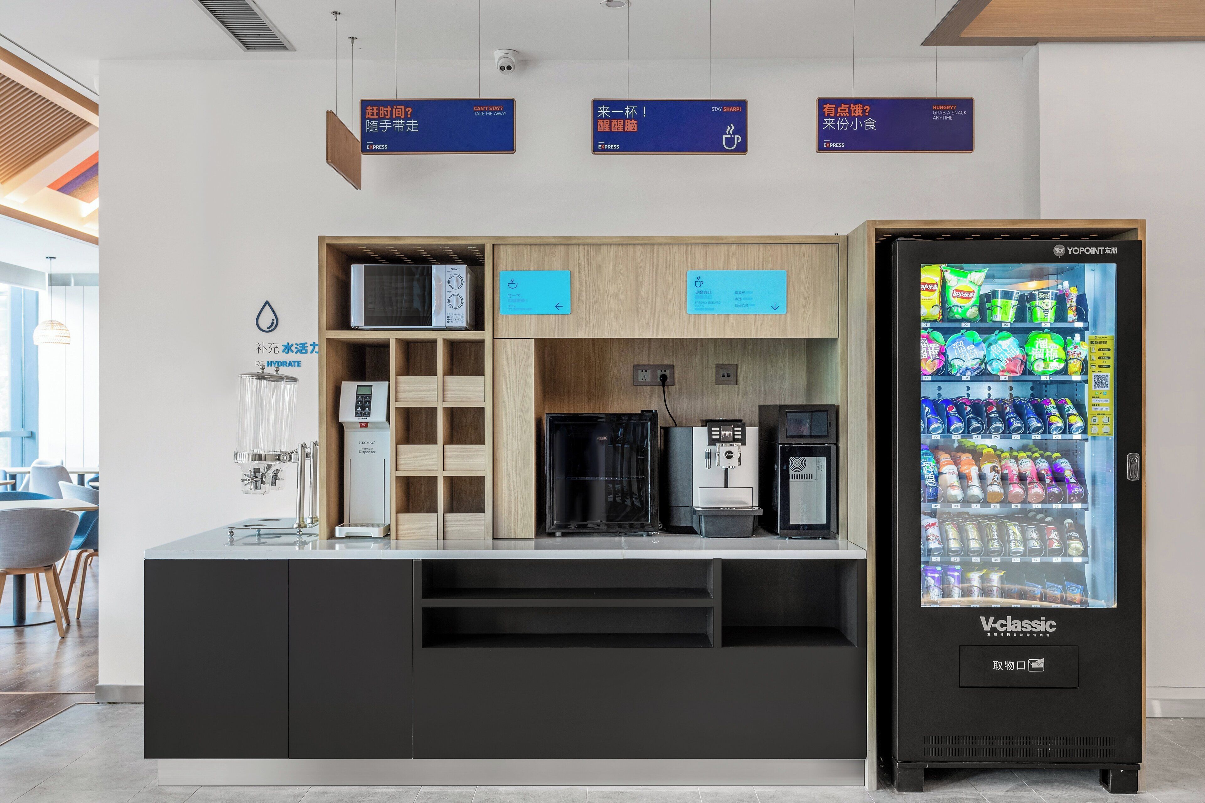 A self-service beverage station with a vending machine, coffee machines, and a hydration station.