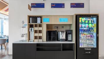 A self-service beverage station with a vending machine, coffee machines, and a hydration station.
