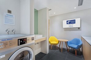 A hotel bathroom with a Haier washing machine, a sink, and a chair. - Holiday Inn Express Dali Xiaguan by IHG (Dali)