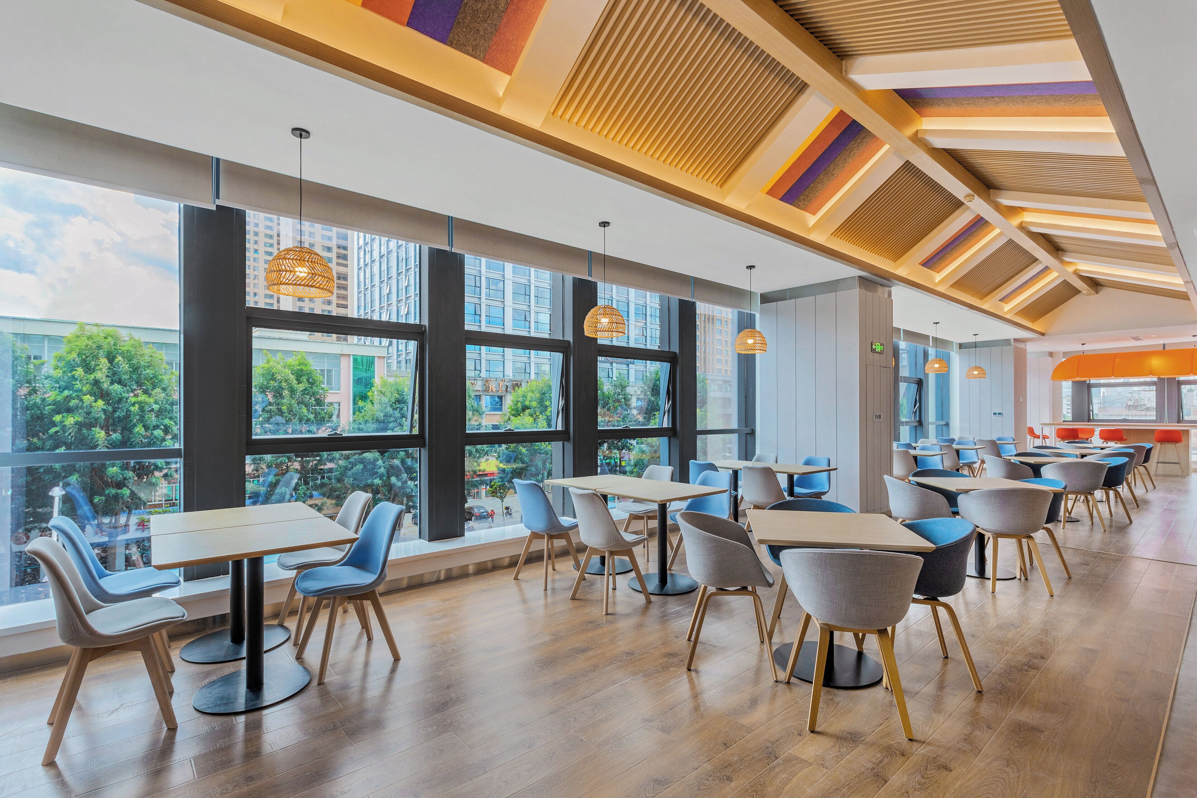 Un comedor moderno con ventanas amplias, piso de madera y sillas contemporáneas.
