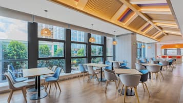Un comedor moderno con ventanas amplias, piso de madera y sillas contemporáneas.