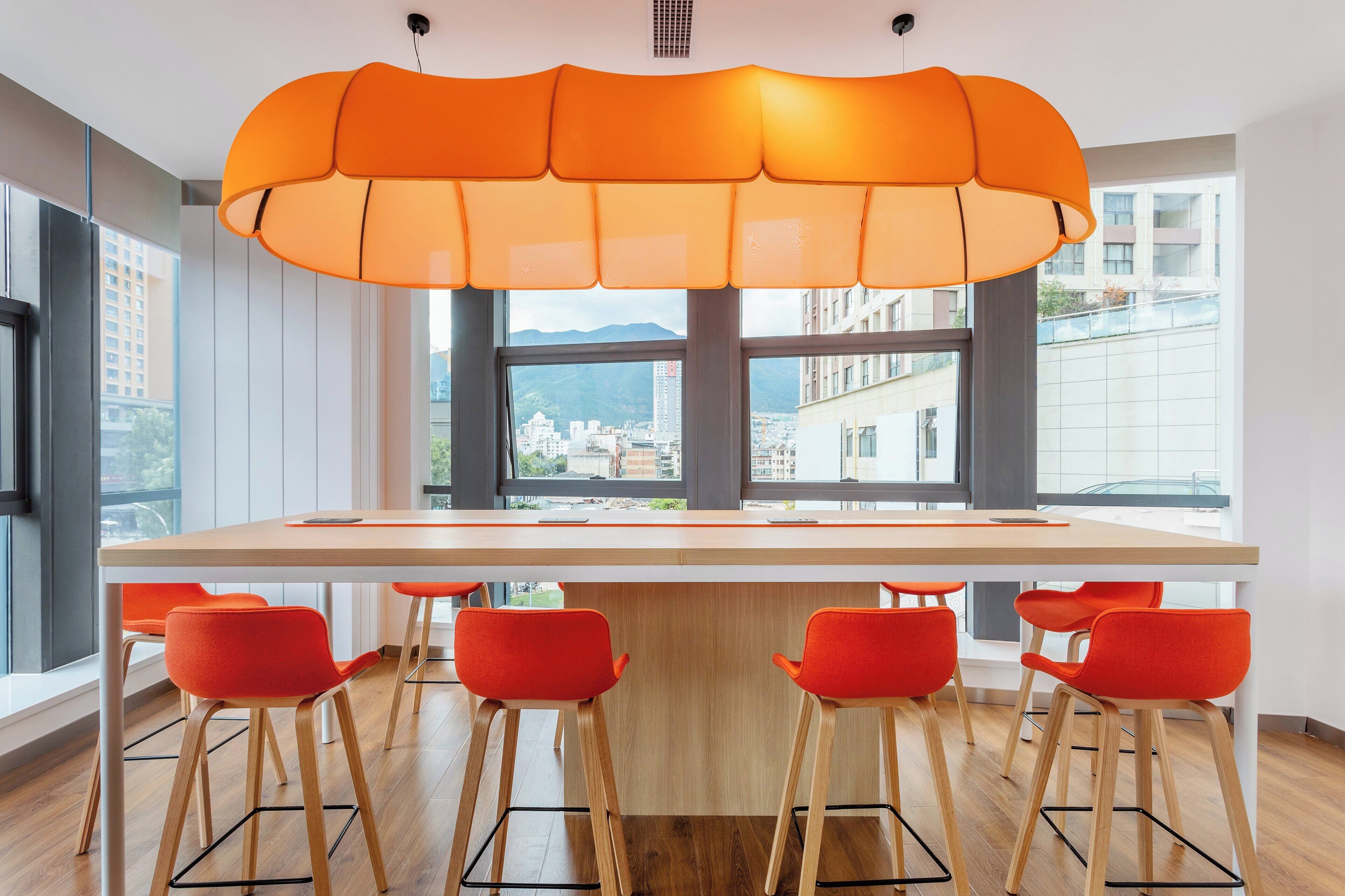 A modern kitchen with a large island, bar stools, and a view of the city through large windows.