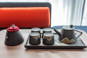 A tea set with four cups and a teapot on a tray, placed on a wooden table with a red cushion in the background. - Holiday Inn Express Dali Xiaguan by IHG (Dali)