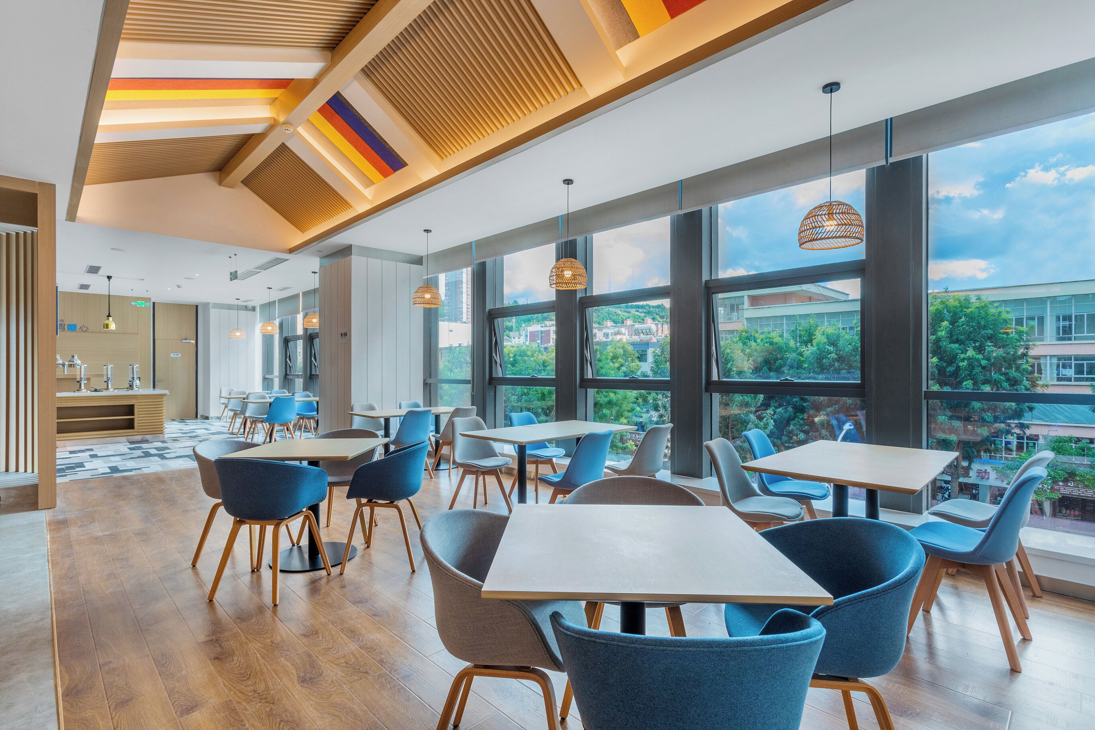 A modern dining area with large windows, wooden flooring, and contemporary furniture.