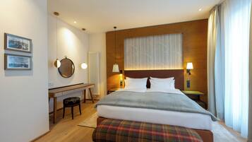 Et moderne hotelværelse med en stor seng, et skrivebord og en bænk.