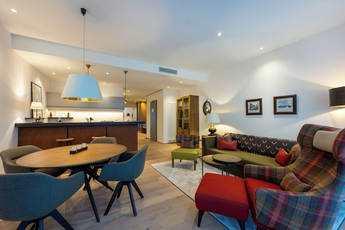 Una sala de estar moderna con sofá, sillas, una mesa de comedor y una zona de cocina.