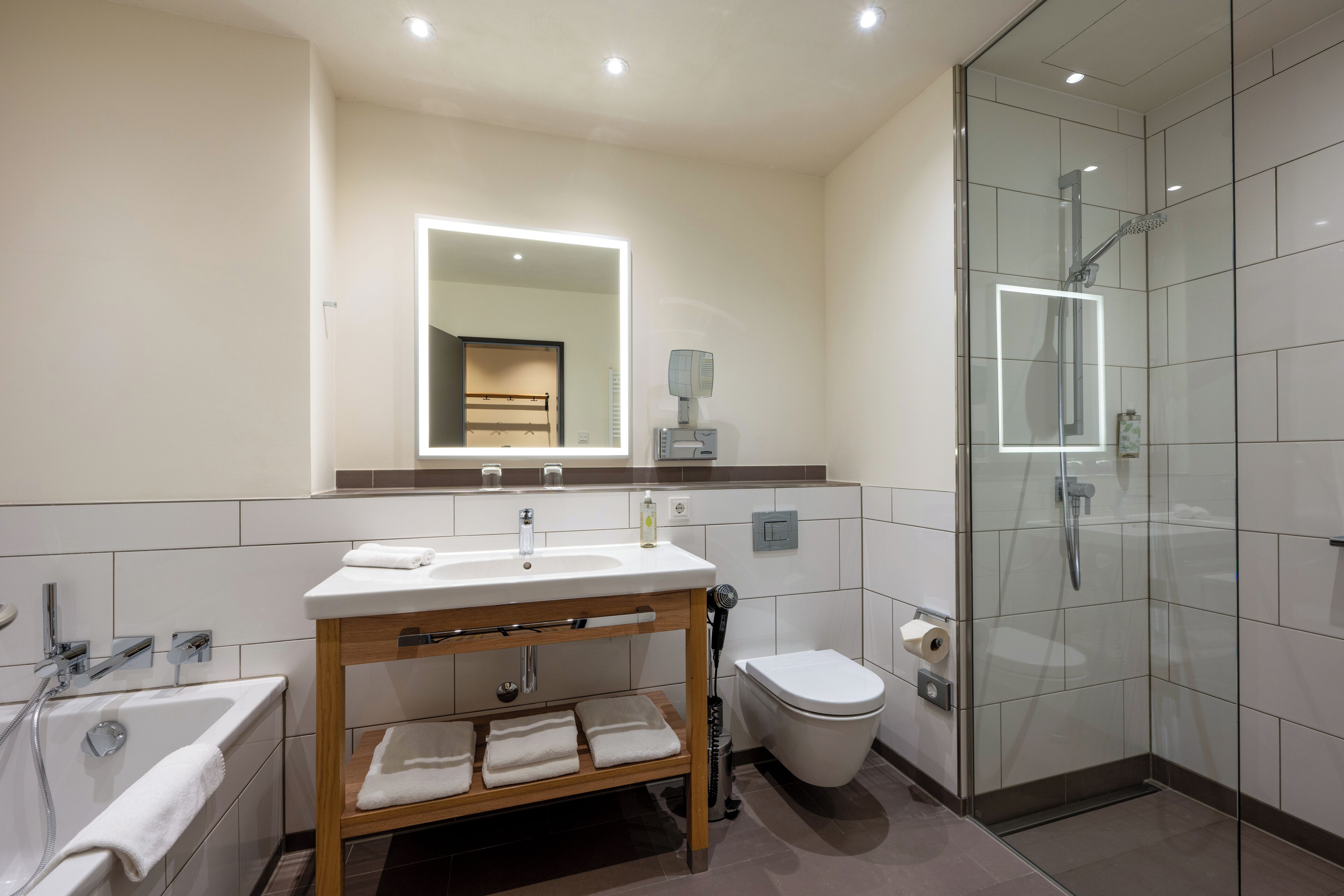 A modern bathroom with a glass-enclosed shower, a vanity with a mirror, a toilet, and a bathtub.