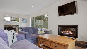 Una sala de estar moderna con chimenea, asientos cómodos y ventanas amplias.