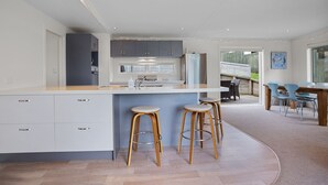 Una cocina moderna con una isla central, taburetes de bar y un comedor con sillas y una mesa.