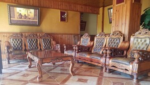 A room with a wooden sofa set, a wooden coffee table, and a patterned floor.