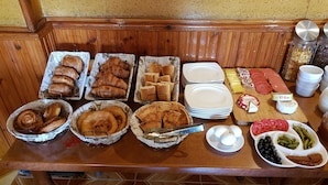 A breakfast buffet with various pastries, bread, cheese, and fruits.