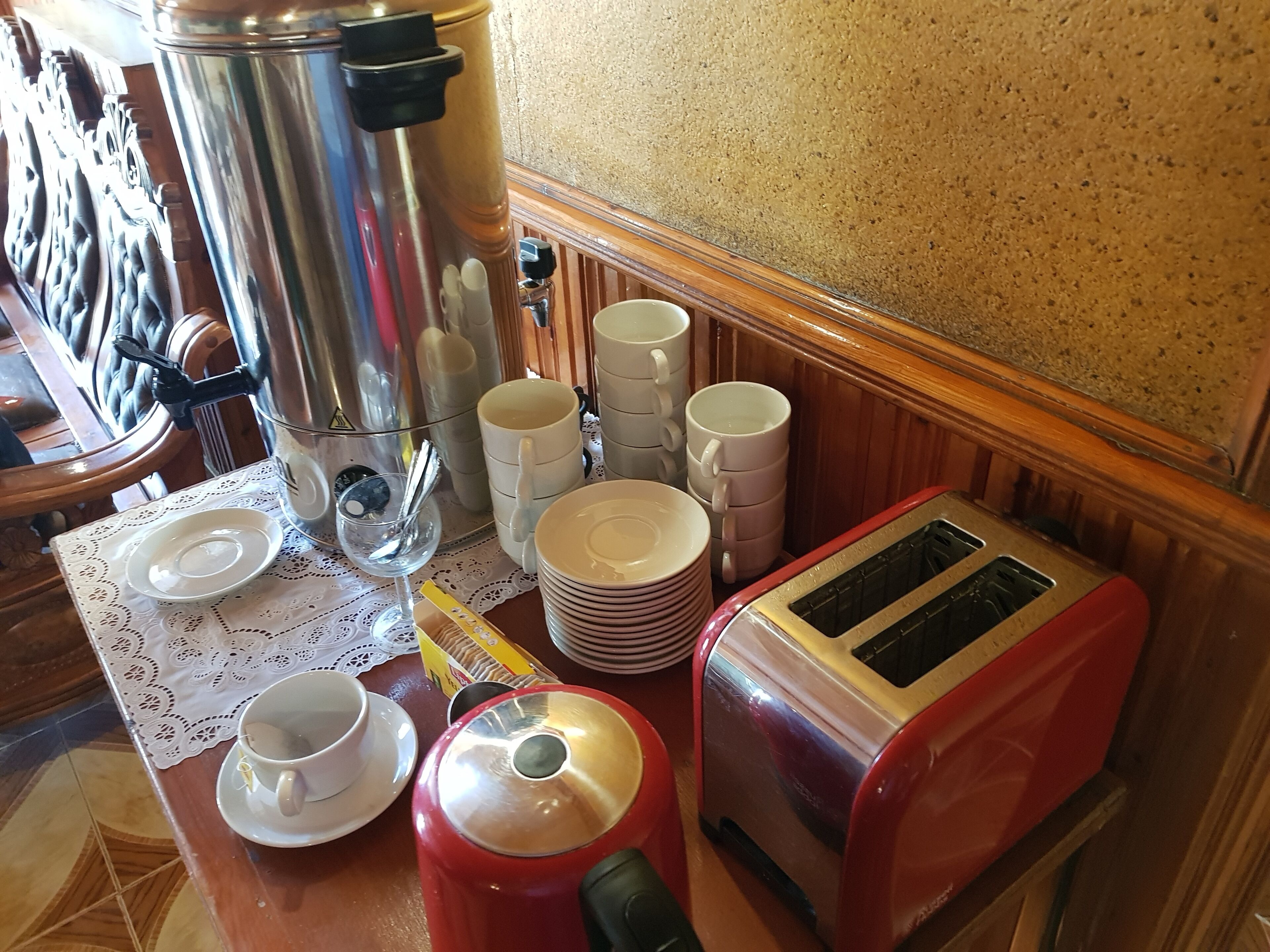 Une petite cuisine équipée d’une machine à café, d’un grille-pain, ainsi que d’une pile de tasses et d’assiettes.