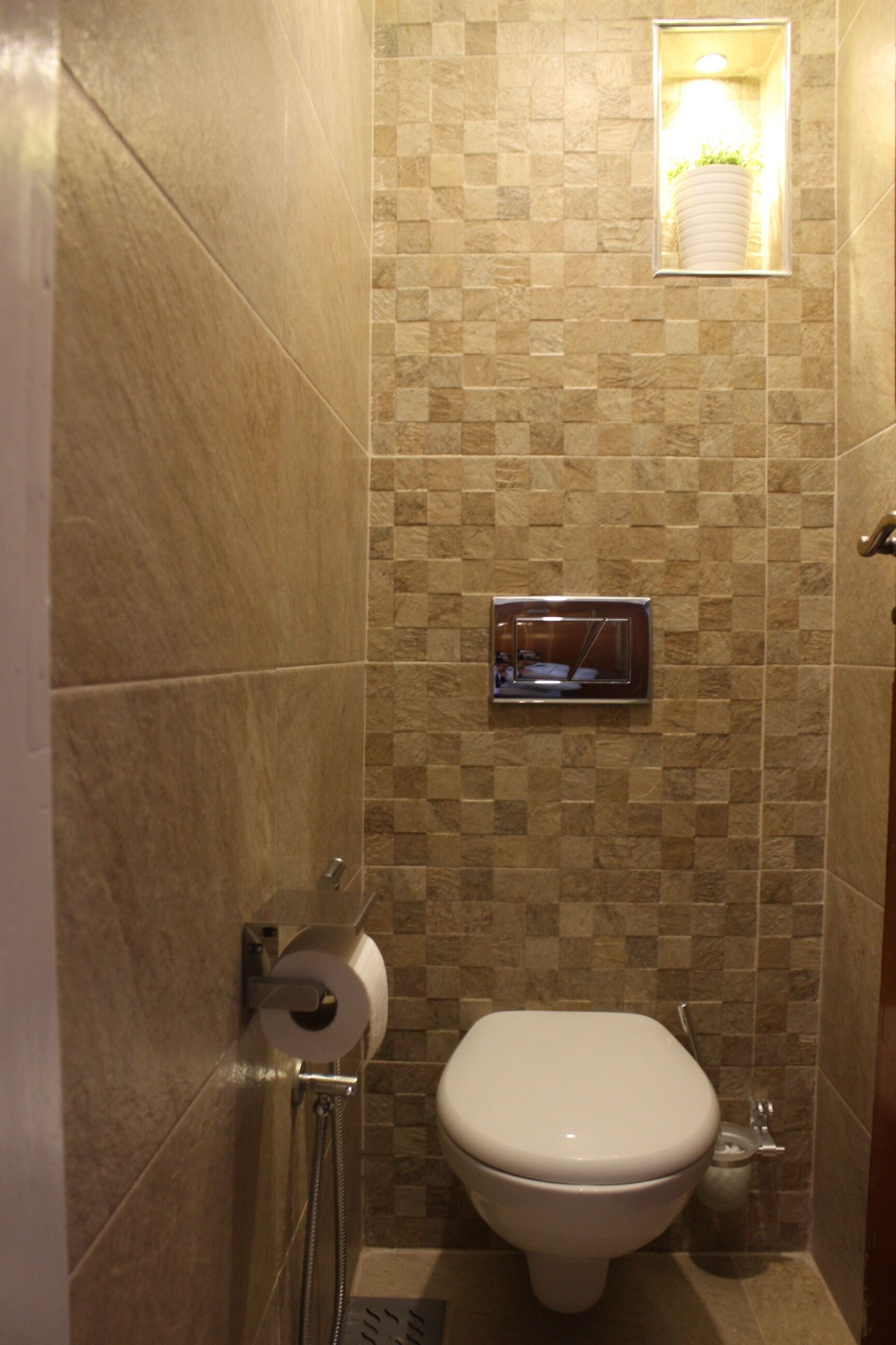 A bathroom with a toilet, a hand dryer, and a towel dispenser.
