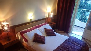 A hotel room with a large bed, two bedside lamps, a wooden headboard, and a view of the outdoors.