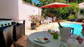 A patio area with a pool, outdoor seating, and a grill.