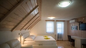 Une pièce avec un plafond en pente, un lit avec une literie blanche, un bureau et une chaise.