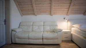 Une chambre avec un canapé beige, une table de chevet avec une lampe et un lit.