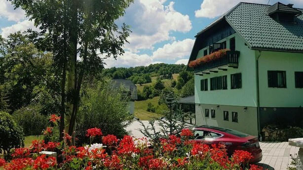 Un immeuble de deux étages, doté d’un toit végétalisé et d’un balcon orné de fleurs rouges.