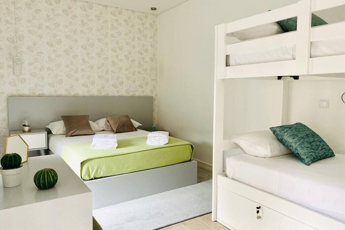 Een slaapkamer met een stapelbed, een nachtkastje met een lamp en een kleine potplant.