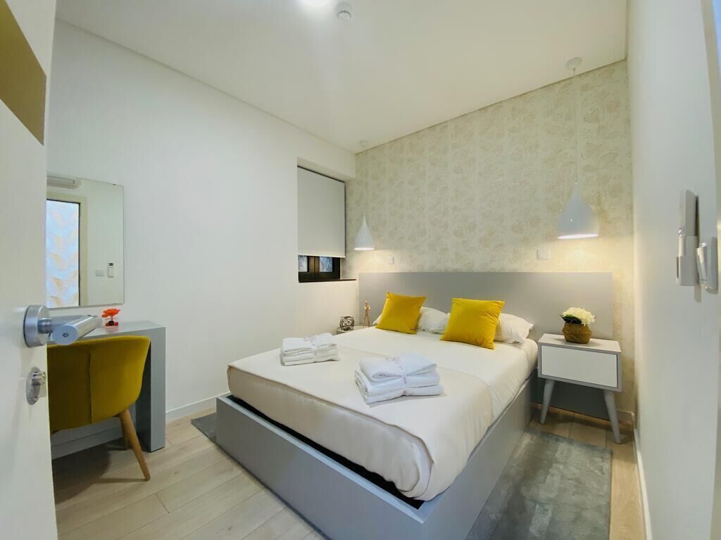 Un dormitorio moderno con una cama grande, mesitas de noche, un escritorio y una silla.