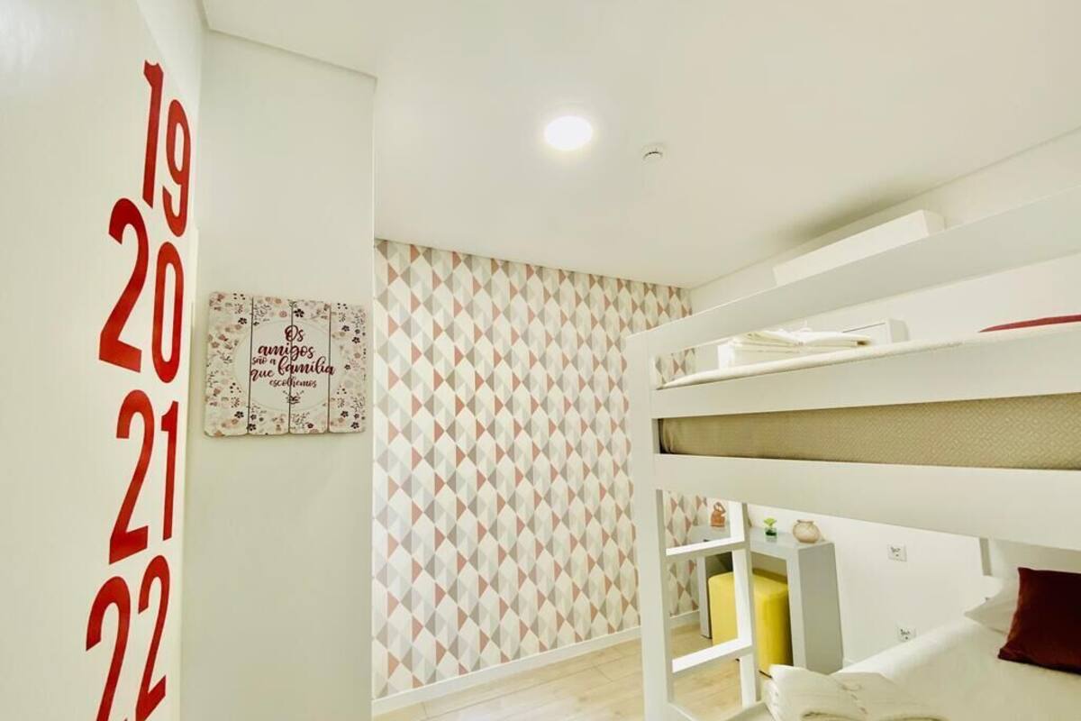 Een hotelkamer met een stapelbed, een wandklok en behangpapier met een geometrisch patroon.