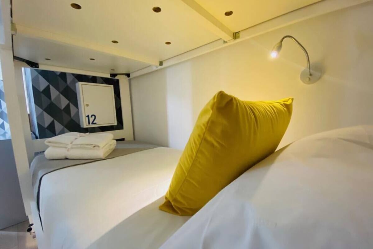 Een hotelkamer met een bed, nachtkastje, wandlamp en een muur met een geometrisch patroon.