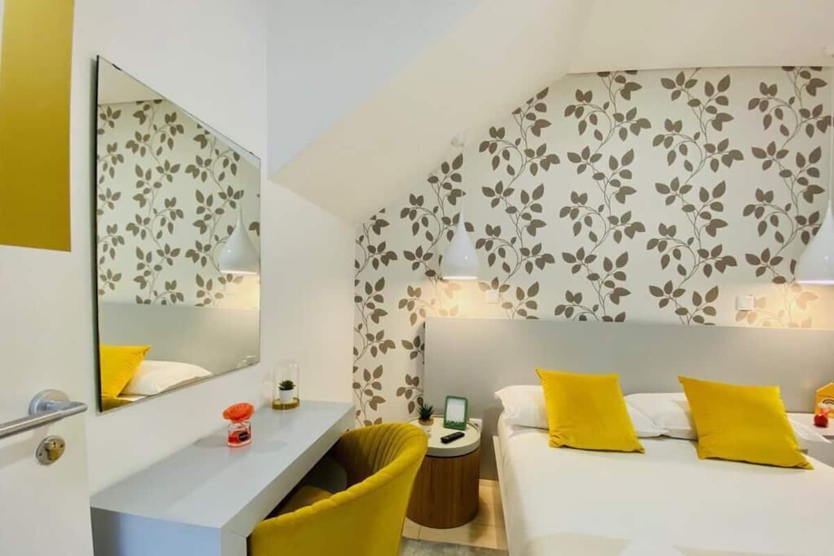 Een hotelkamer met een bed, nachtkastje, stoel en spiegel.