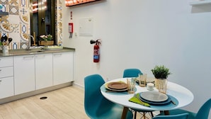 A modern kitchen with white cabinets, a sink, and a dining area with a round table and blue chairs.
