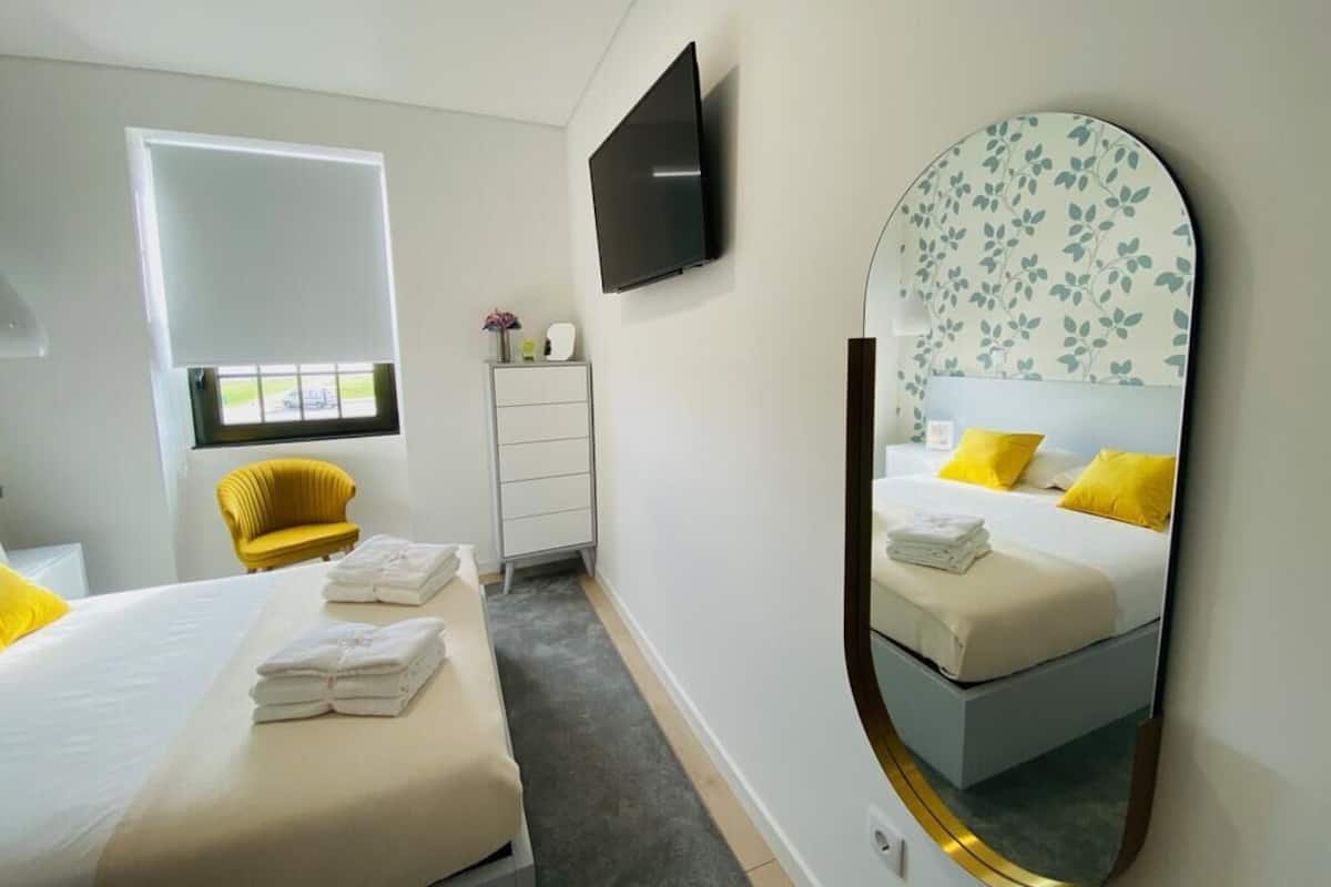 Een moderne hotelkamer met een bed, een stoel, een televisie en een grote spiegel.