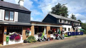 A two-story building with a brick facade, large windows, and outdoor seating with umbrellas. - The Climbers Inn (Glencar)