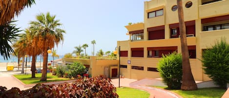 A multi-story hotel with a modern design, featuring balconies, a central courtyard, and palm trees.