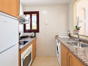 A compact kitchen with a refrigerator, stove, oven, microwave, and a washing machine. - 1162 Apartment Burriana (Nerja)