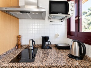 Eine Küche mit einer Balay Dunstabzugshaube, einer Mikrowelle, einer Kaffeemaschine und einem Wasserkocher auf einer Arbeitsplatte aus Granit.