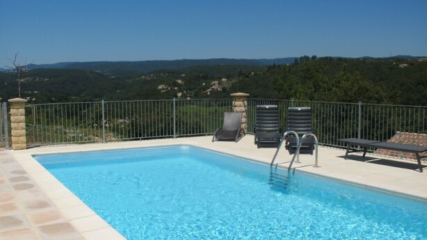 A swimming pool with a view of hills and a fenced area with lounge chairs. - Beautiful newly built house with private pool in the Ardèche (Chassagnes)