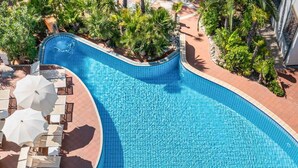 A large, curved swimming pool with tiled edges, surrounded by lounge chairs and umbrellas. - Park Hotel Pineta (Caorle)